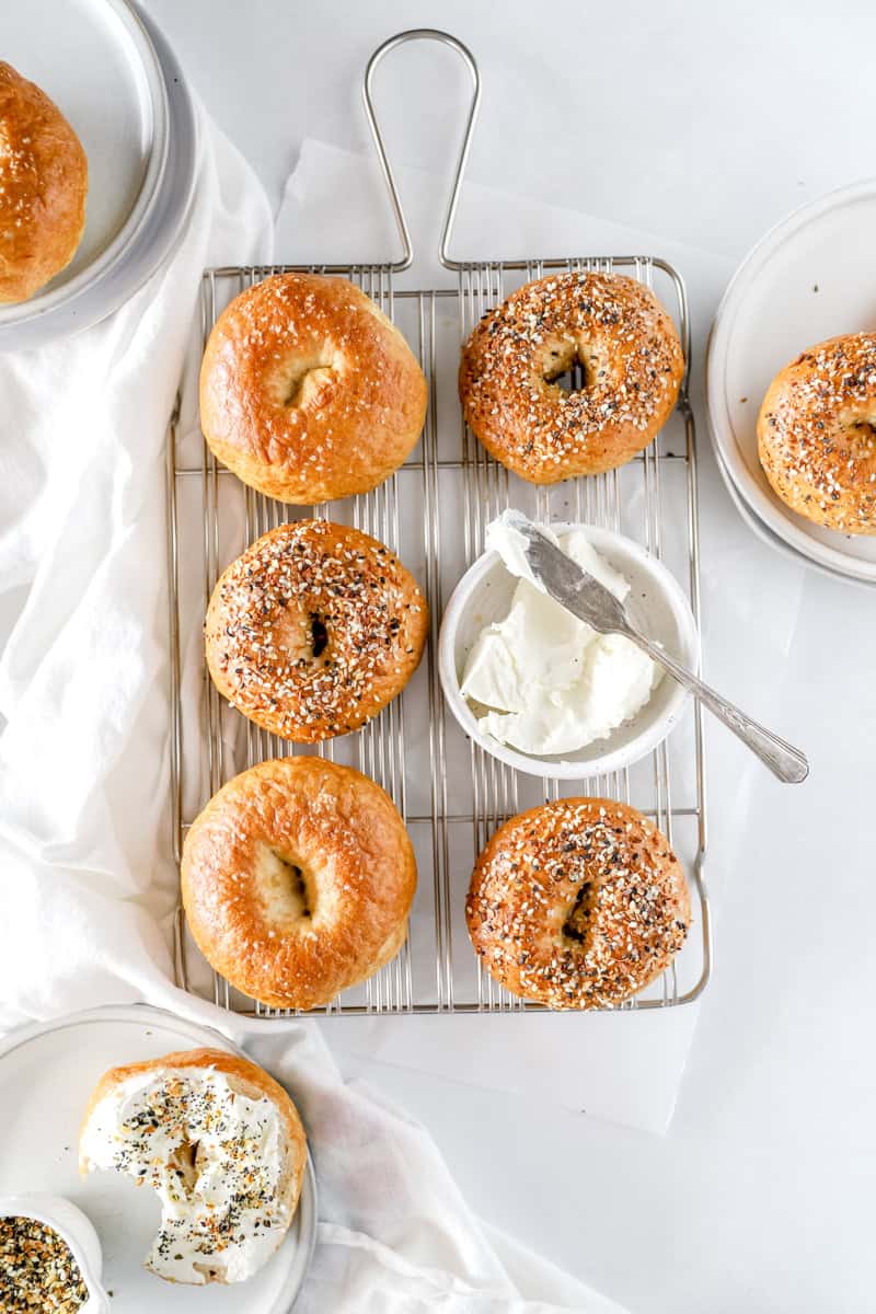 Sourdough bagels on a cooling rack with cream cheese.