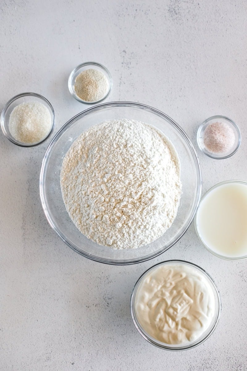 Ingredients for sourdough bagels in glass prep bowls.