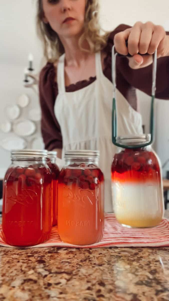 Using a jar lifter to transfer the hot cranberry juice from the canner to the counter.