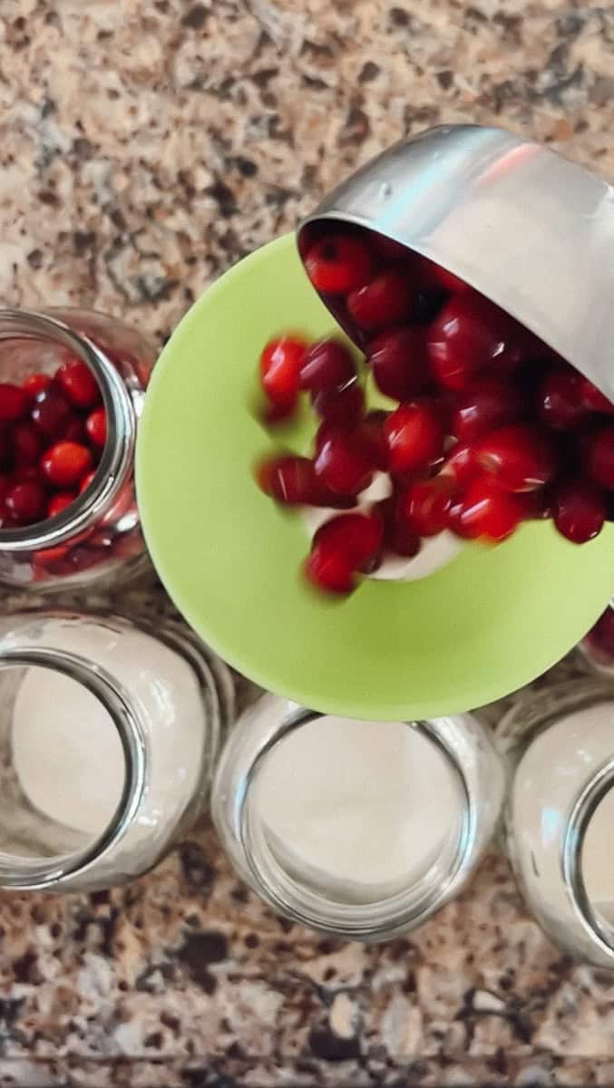 Step 4 of canning cranberries is adding sugar and cranberries to the jars.