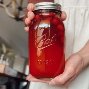 Canning cranberry juice recipe, woman holding a jar of homemade cranberry juice.