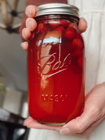 Canning cranberry juice recipe, woman holding a jar of homemade cranberry juice.