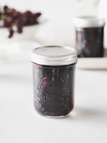 A pint jar of homemade grape juice from this grape juice canning recipe.