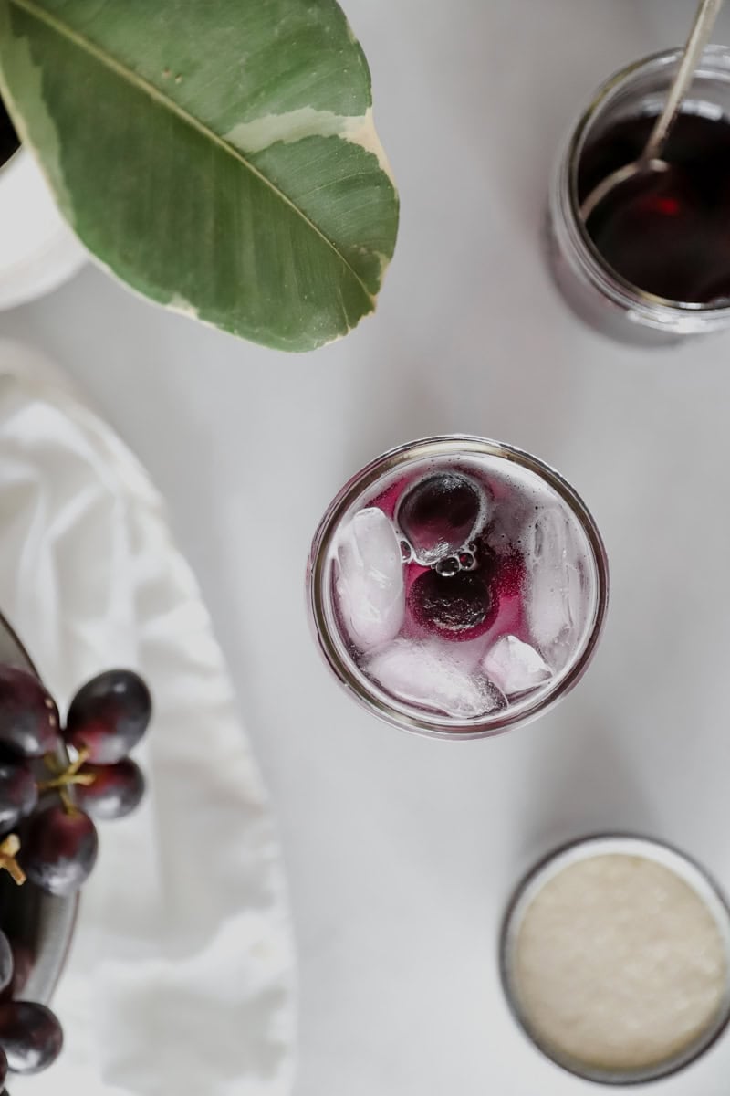 A top view of homemade grape juice in a mason jar with ice.