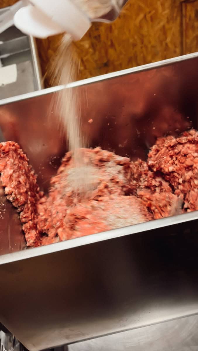 Step 3 of making venison summer sausage is mixing the water and seasonings with the ground venison.