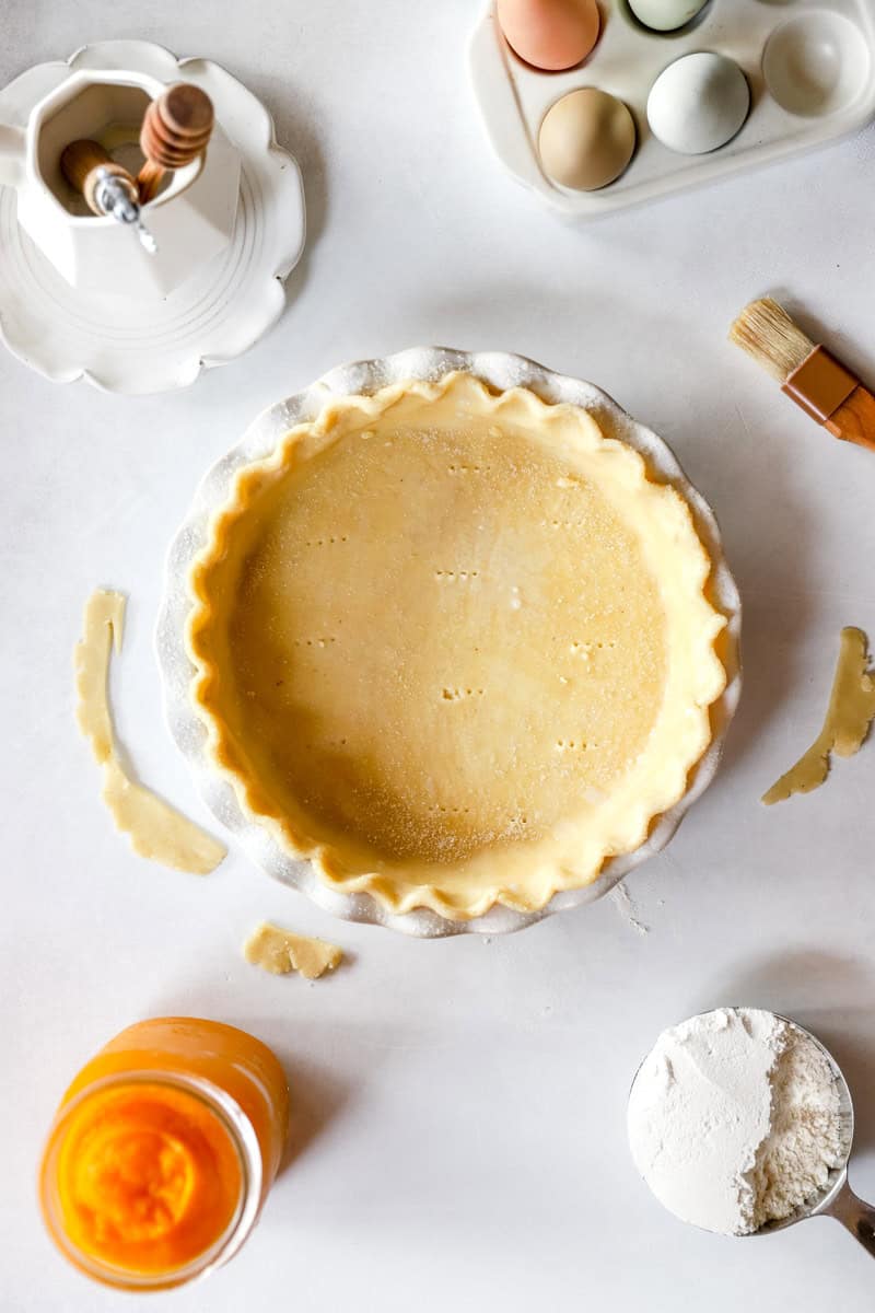 Step 1 of making a pumpkin pie is sourdough pie crust top view with ingredients around it.