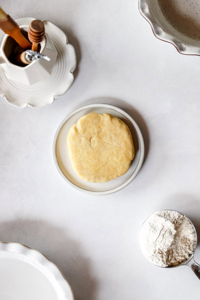 A sourdough pie crust disc on a white platter.
