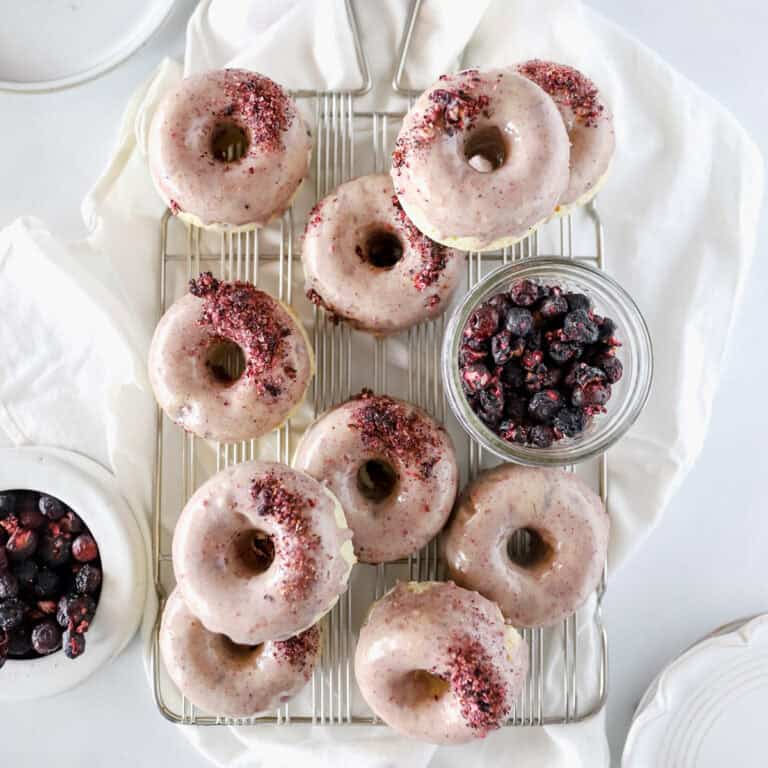 Blueberry donut recipe showing 12 donuts cooling on a wire rack.