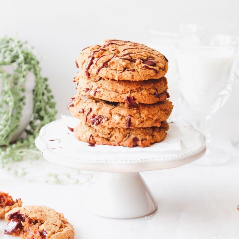 A pedestal cake plate stacked high with Bourbon Chocolate Chunk Cookies With Pecans.