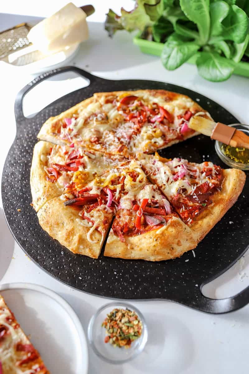 An angled view of a grinder pizza on a cast iron pan.