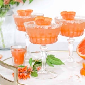 A salty dog trio in coupe glasses garnished with grapefruit.s