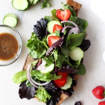Seasonal salads from the garden showing a salad with strawberries, red onion, cucumbers, greens.