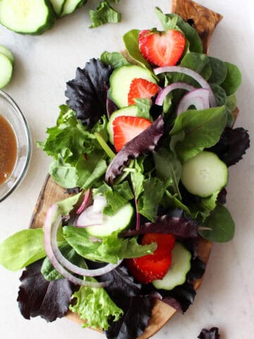 Seasonal salads from the garden showing a salad with strawberries, red onion, cucumbers, greens.