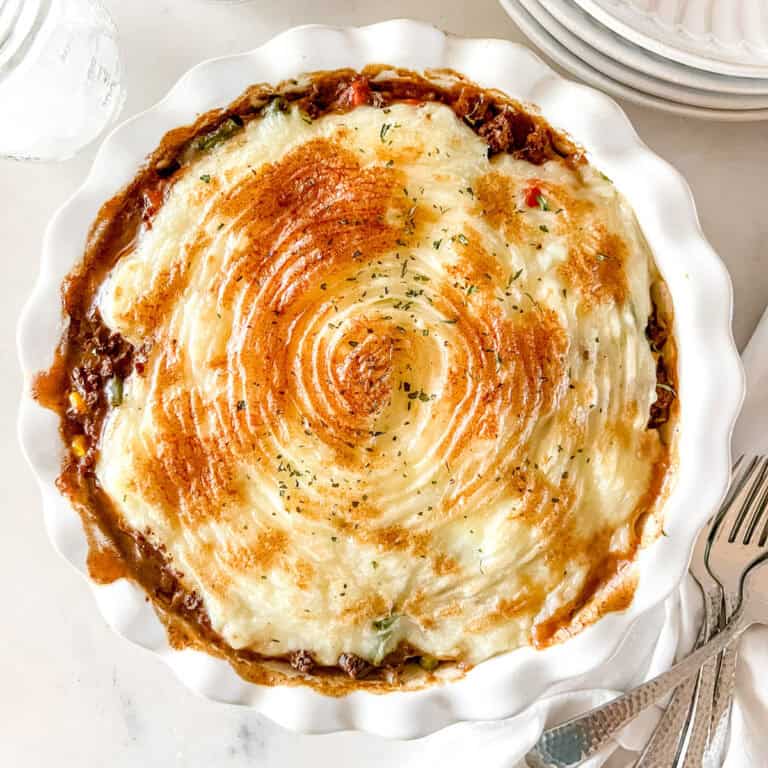 A white pie pan filled with venison shepherd's pie, topped with mashed potatoes.