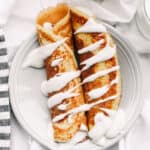 A plate of 20 minute sourdough crepes drizzled with whipped cream.