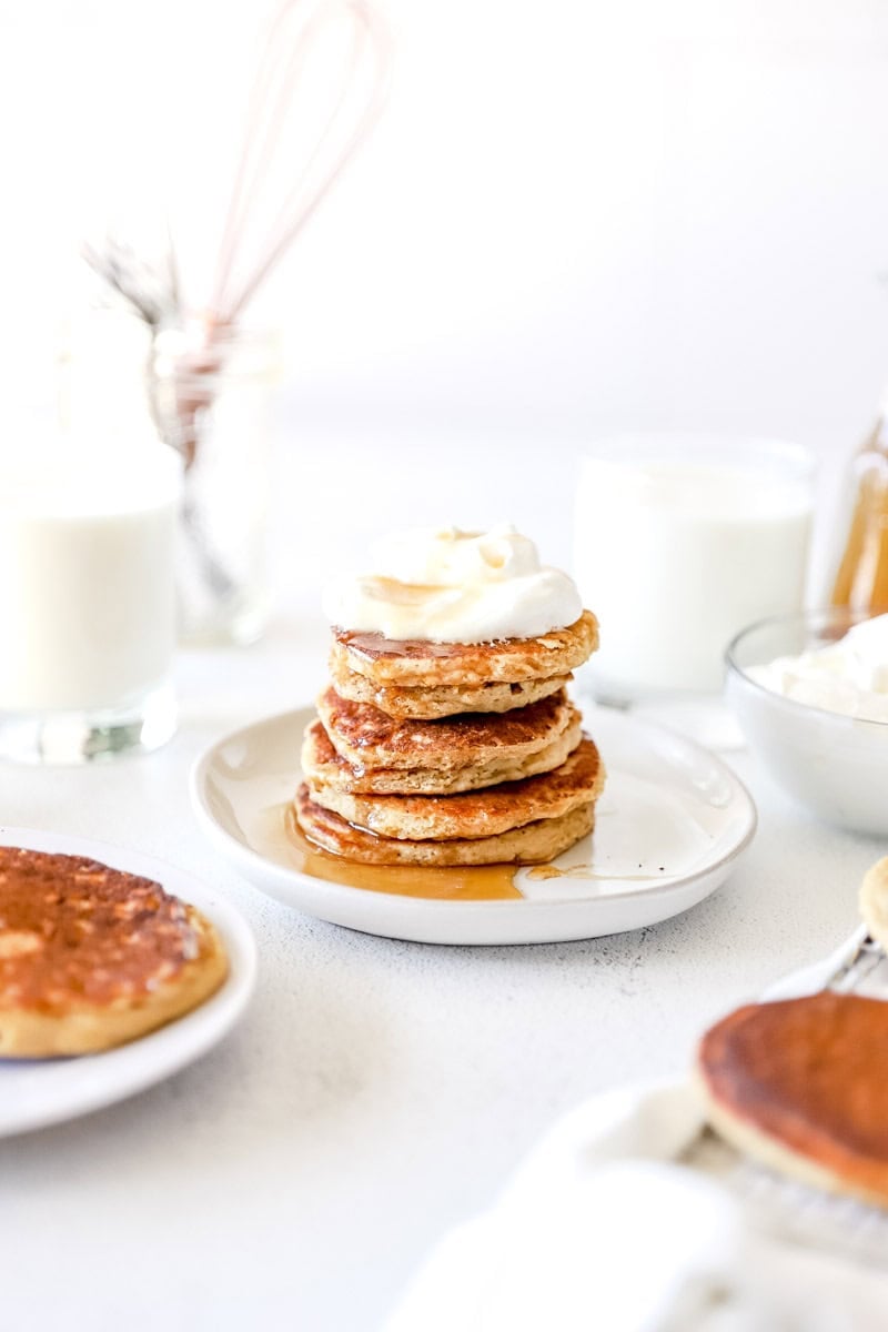 Honey Oat Sourdough Discard Pancakes stacked on a plate with whipped topping.
