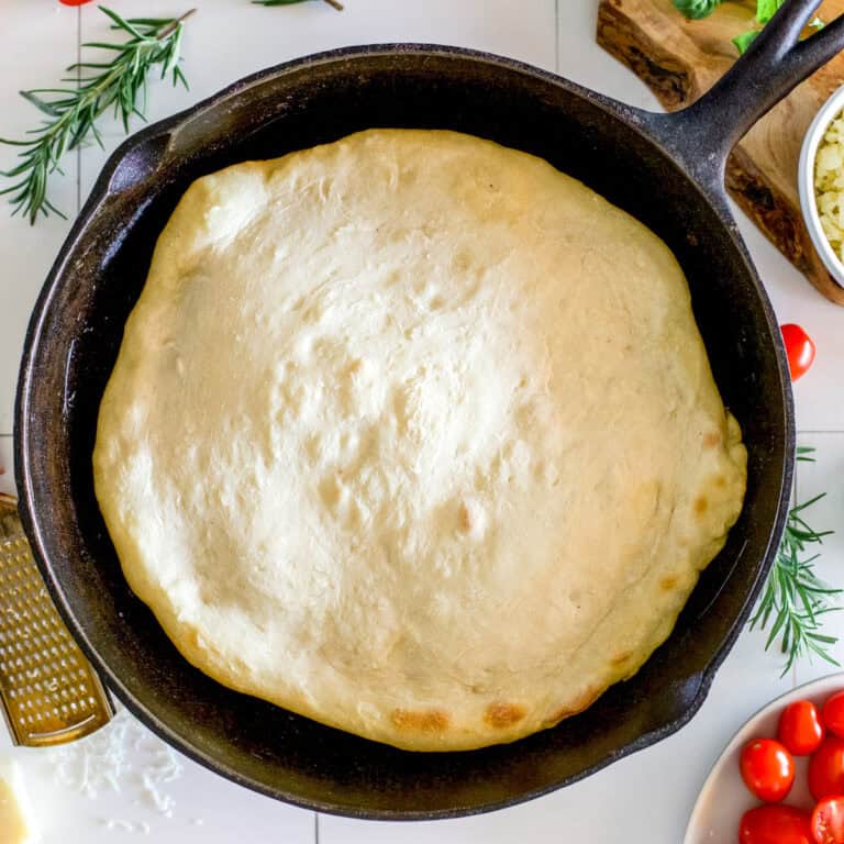 A sourdough pizza crust in a cast iron skillet that has been par-baked.