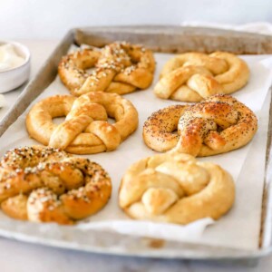 An angled side view of sourdough pretzels on a baking sheet.