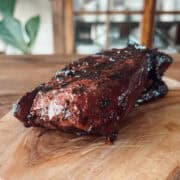 A freshly grilled venison steak on a wooden cutting board cooked in an all-purpose marinade.