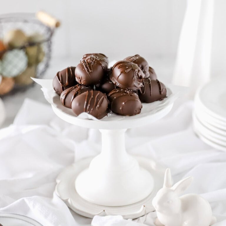 Chocolate peanut butter eggs that look like Reese's peanut butter cups on a tall platter.