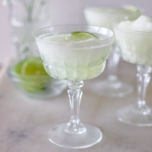 A coupe glass of fresh margaritas garnished with lime.