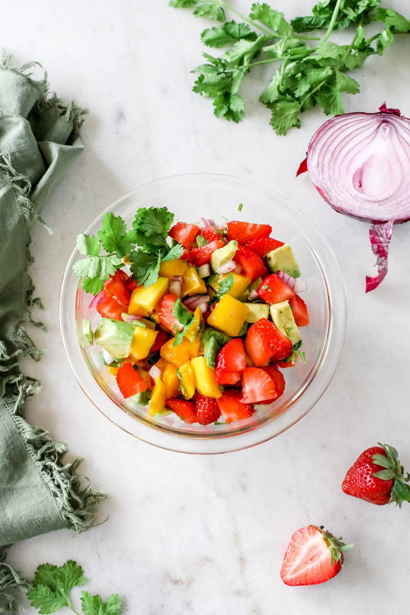 Step 2 of how to make mango salad is adding the ingredients to a bowl and tossing with the honey lime dressing.
