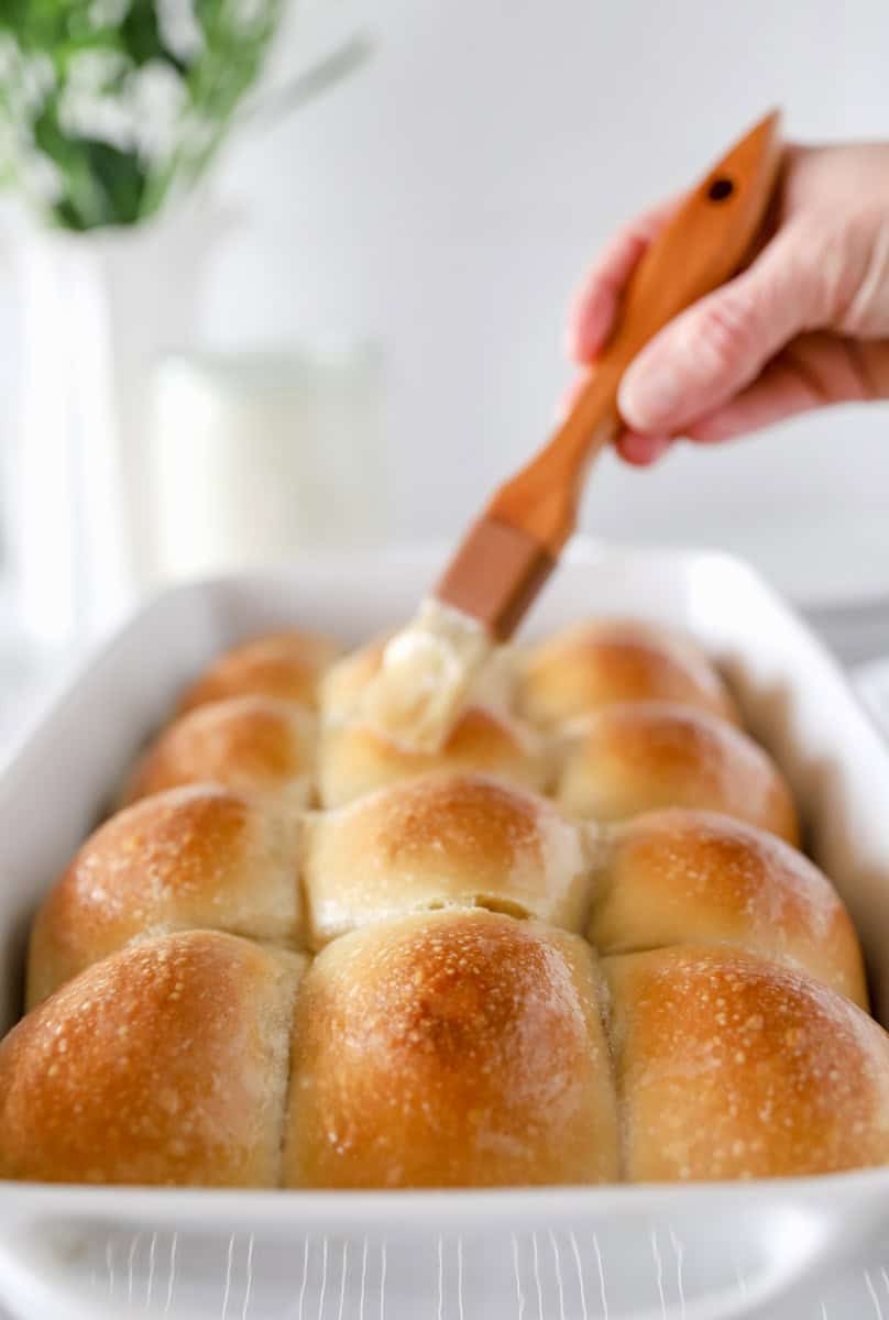 Step 6 of making homemade sourdough rolls is brushing the tops with butter while still warm.