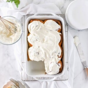 A top view of a white baking dish with sourdough cinnamon rolls with cream cheese frosting.