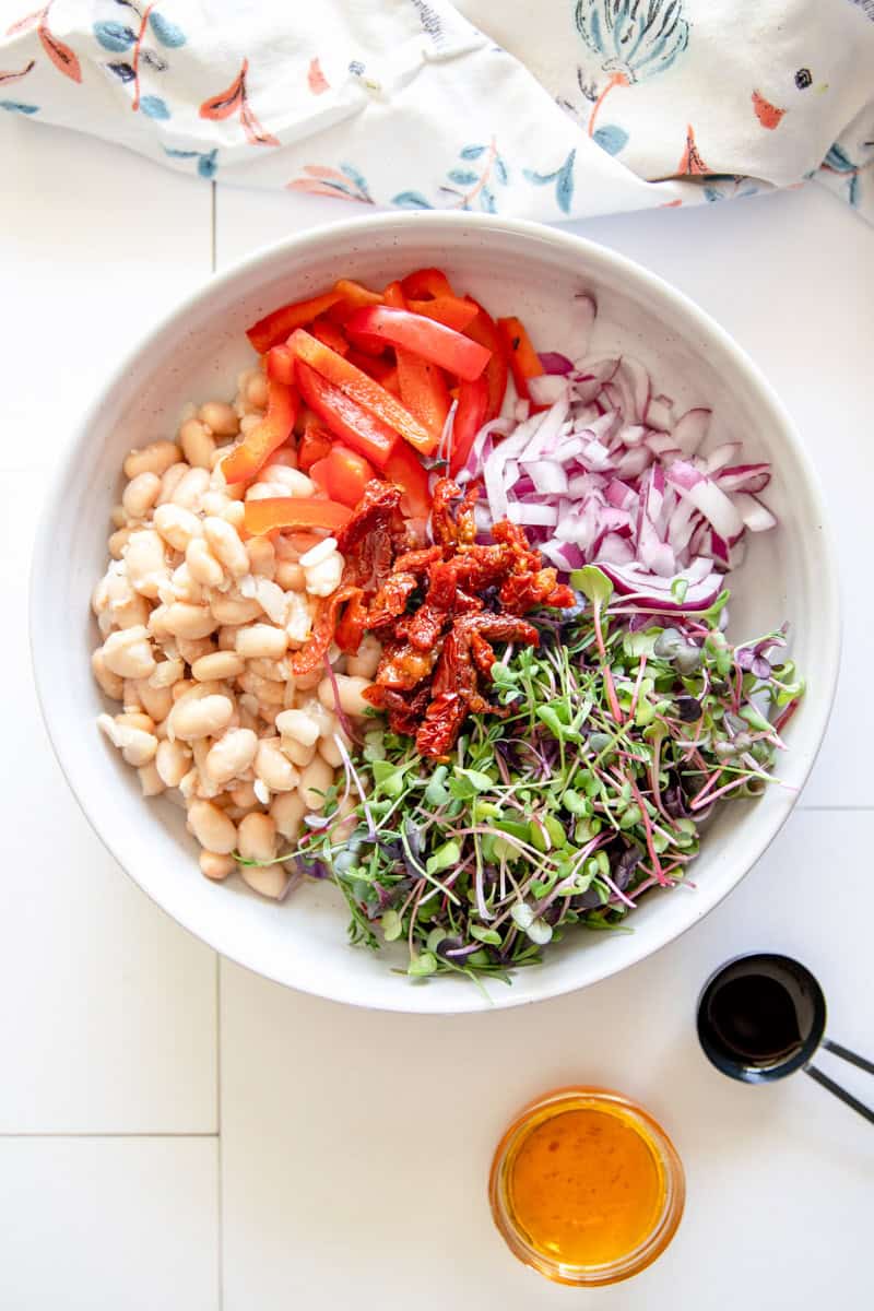 Step 2of making this Cannellini Bean Recipe is mixing the dressing and adding the ingredients to a large bowl.