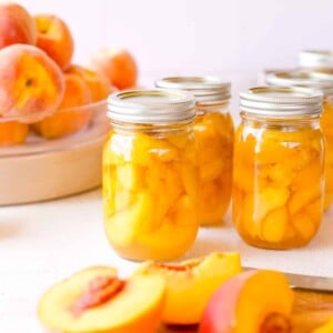 How to Can Peaches - Beginner Peach Canning Recipe showing jars of fresh canned peaches.