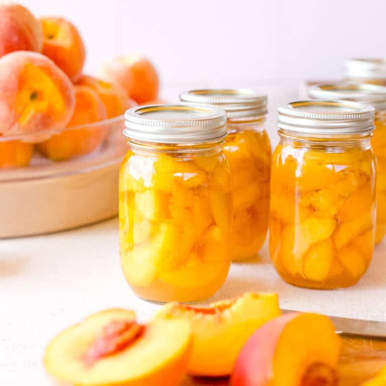 How to Can Peaches - Beginner Peach Canning Recipe showing jars of fresh canned peaches.