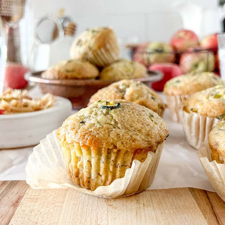 A close up view of a sourdough apple zucchini muffin with the wrapper slightly unwrapped to show the detailed crumb.