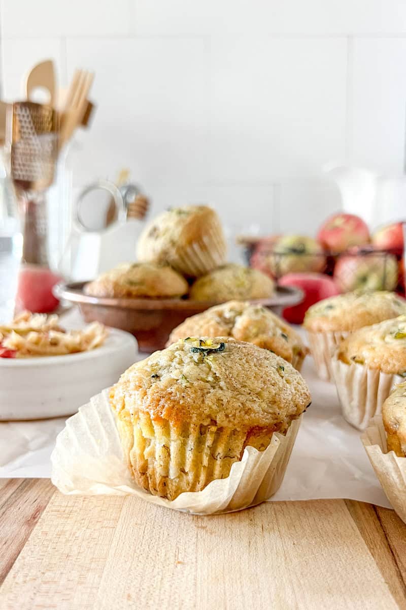 A side view of a sourdough apple zucchini muffin with the parchment wrapper slightly open.
