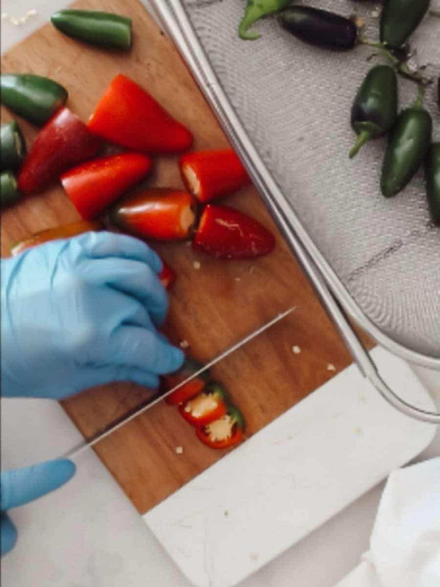 Cutting peppers into pieces wearing gloves.
