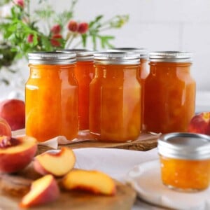 A close up of several jars of peach preserves recipe for canning.