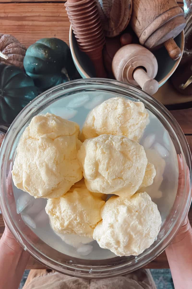 A top view of a big bowl of ice water filled with balls of freshly churned butter.