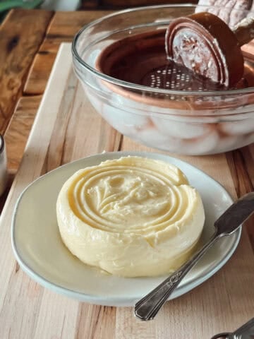 How to make homemade butter with a fresh pressed raw cream butter on a plate with a butter knife.
