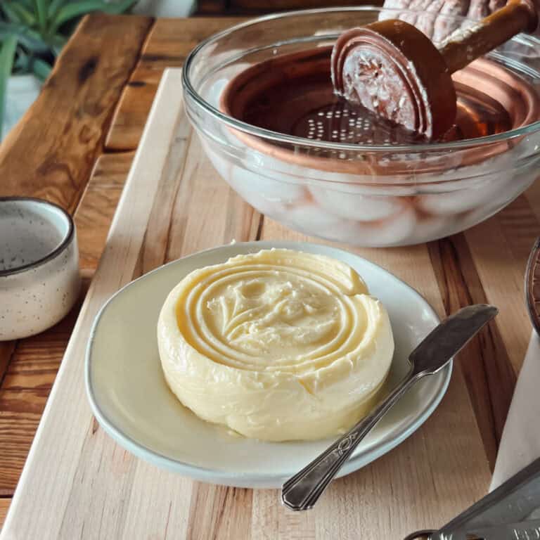 How to make homemade butter with a fresh pressed raw cream butter on a plate with a butter knife.