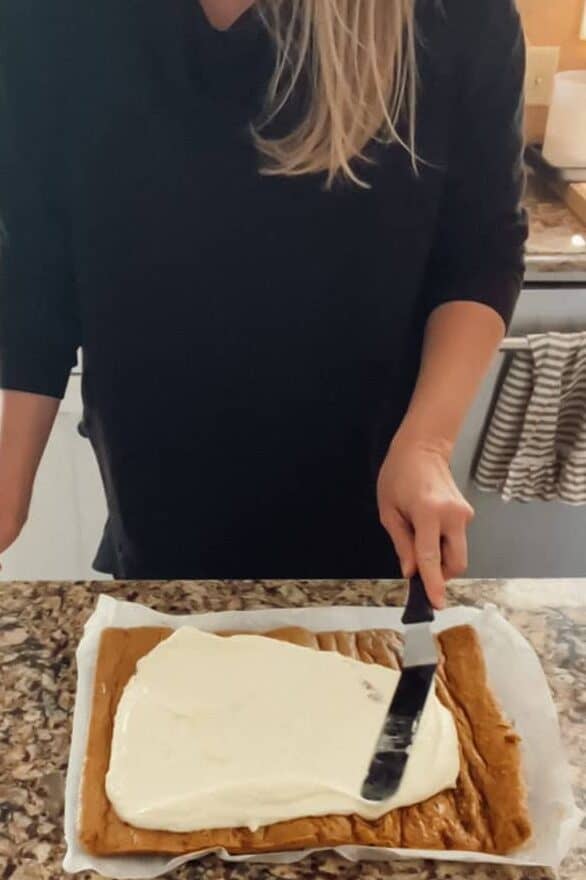 Step 6 of making a pumpkin roll is spreading the cream cheese filling and rolling.