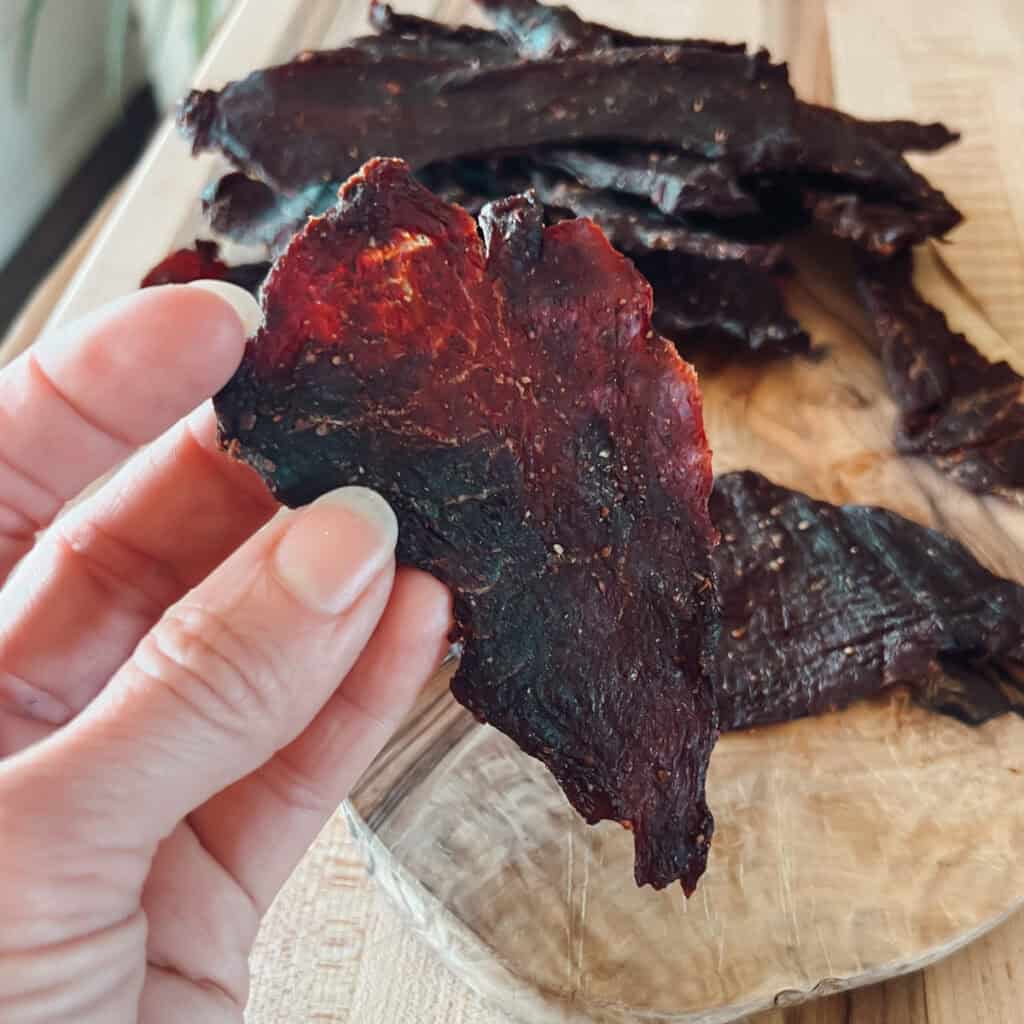 A close up view of deer meat venison jerky being held.