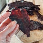 A close up view of deer meat venison jerky being held.