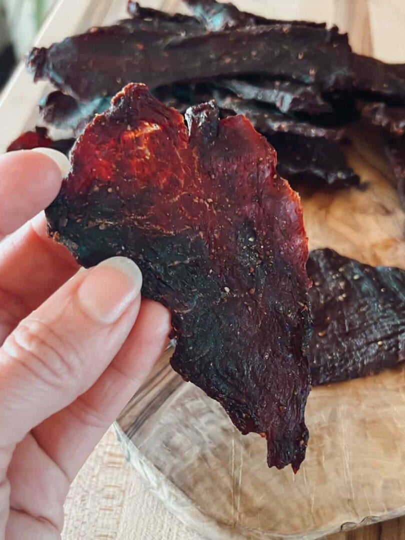 A close up view of deer meat venison jerky being held.