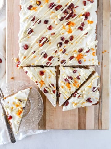 A top view of a batch of sourdough bliss bars with orange zest, dried cranberries and a white chocolate drizzle.