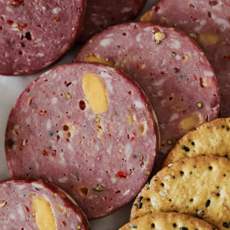 A close up view of sliced smoked venison jalepeno cheddar summer sausage showing the detail of the spices.