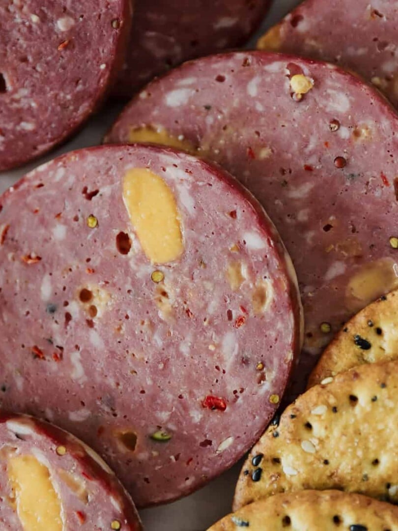 A close up view of sliced smoked venison jalepeno cheddar summer sausage showing the detail of the spices.