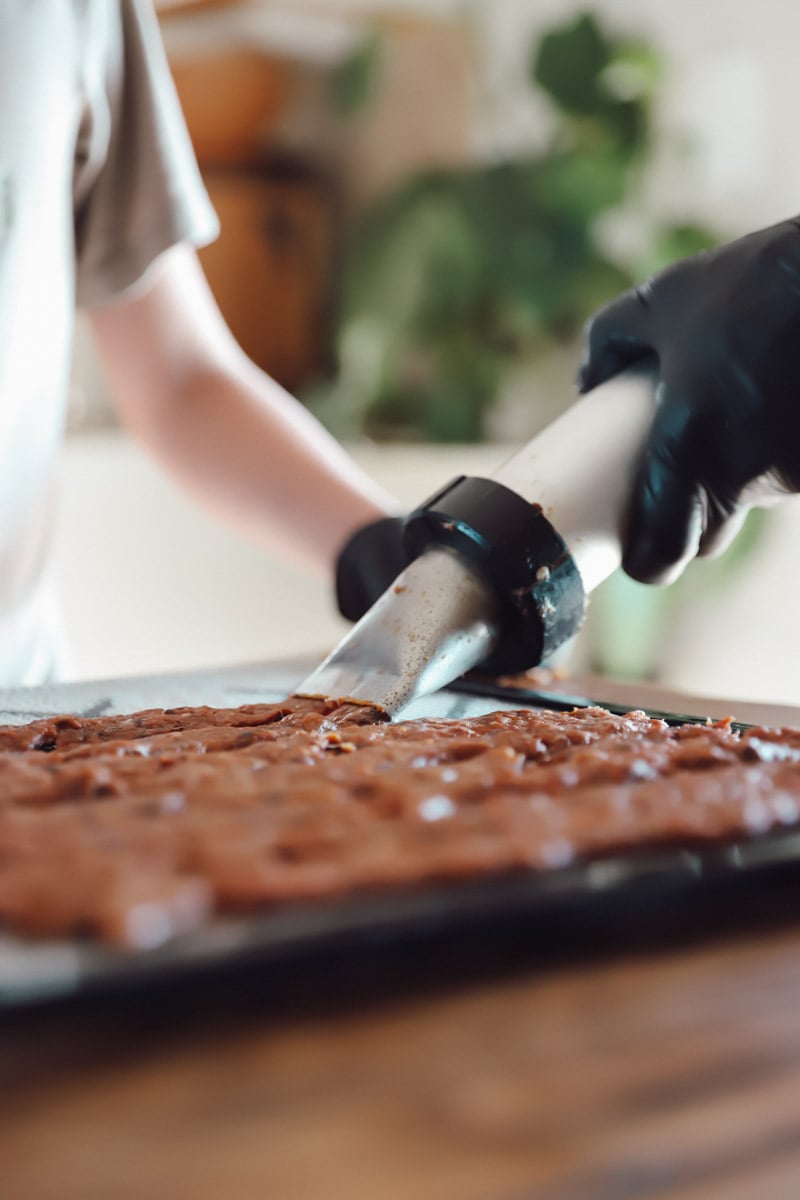 Using a jerky gun to load the dehydrator trays with beef jerky.