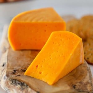 A picture of a sliced wheel of Colby cheese on a cutting board showing the detail of the cheese.