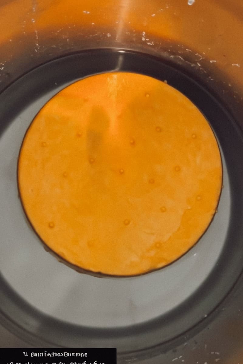 A wheel of Colby cheese floating in a brine in a large stock pot.