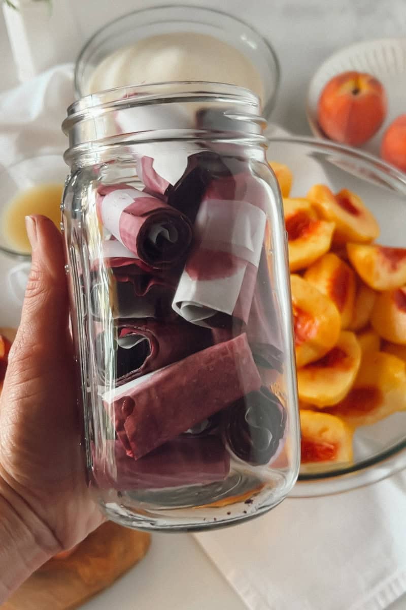 A glass jar with rolled up fruit roll-ups.