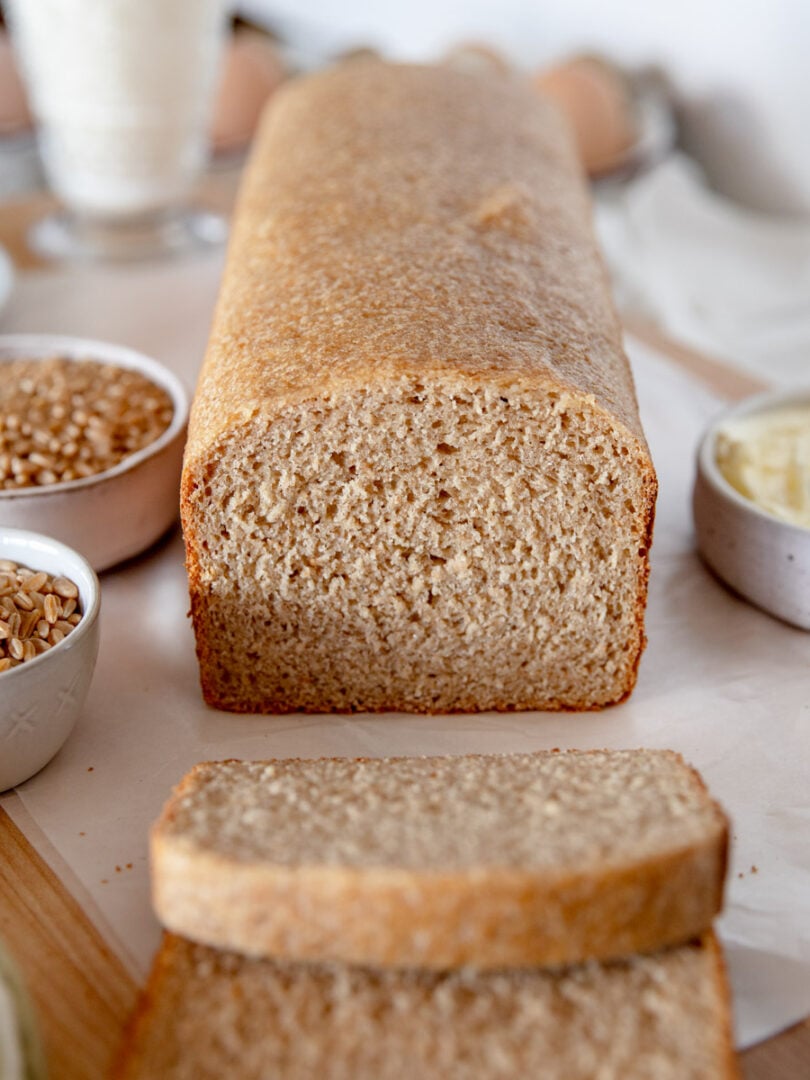 Close-up of sliced whole wheat sourdough sandwich bread showing soft, tight crumb and golden color.